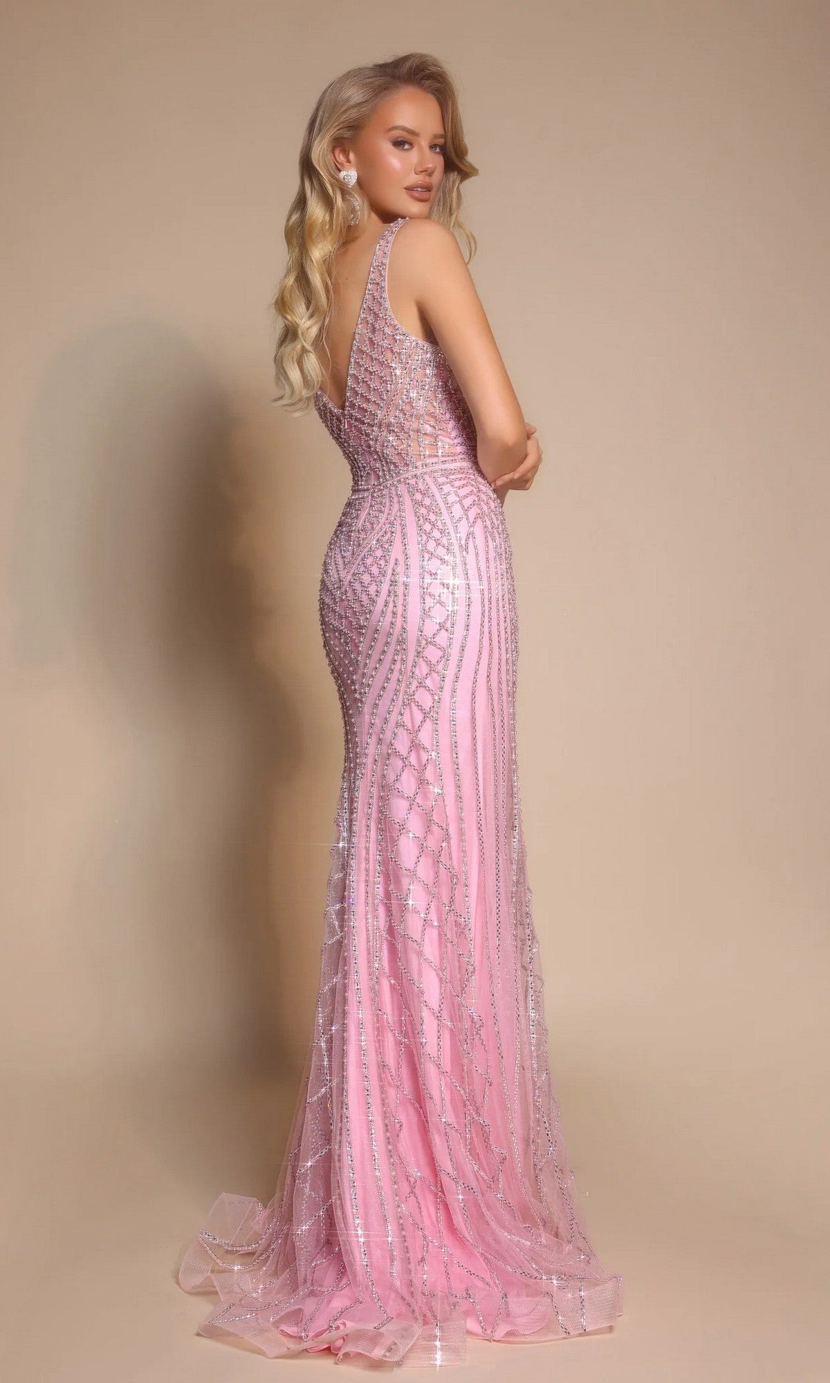 A woman in the Portia and Scarlett PS26089 long formal dress with silver embellishments stands facing away, looking over her shoulder against a beige background.